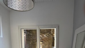 A dining area with a table set for two, a view of a brick wall, and a hanging light fixture.