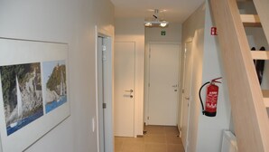 A hallway with a fire extinguisher, a framed photo, and a door.