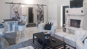 A modern living room with a fireplace, white furniture, and abstract art on the walls. - 2 bedroom stunning home in Roma (Roma)