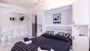 A modern bedroom with a large bed, white furniture, and a framed picture on the wall. - 2 bedroom stunning home in Roma (Roma)