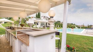 An outdoor kitchen area with a pool and a white house in the background. - 2 bedroom stunning home in Roma (Roma)