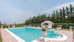 A swimming pool with lounge chairs, a gazebo, and a decorative urn. - 2 bedroom stunning home in Roma (Roma)
