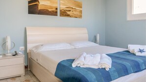 A neatly made bed with a blue and white striped blanket, white pillows, and two rolled towels on the side. - 5 bedroom amazing home in Pachino (Pachino)