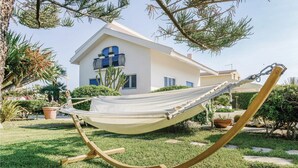 A hammock in a garden with a white building in the background. - 5 bedroom amazing home in Pachino (Pachino)