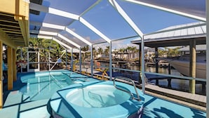 Área de piscina com duas banheiras de hidromassagem e vista para barcos atracados num porto de recreio.