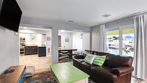 Uma sala de estar moderna com um sofá de couro marrom, uma mesa de centro verde e vista para a piscina.