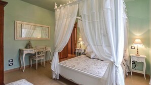 Une chambre à coucher avec un lit à baldaquin, une table de chevet avec une lampe, une commode et un miroir.