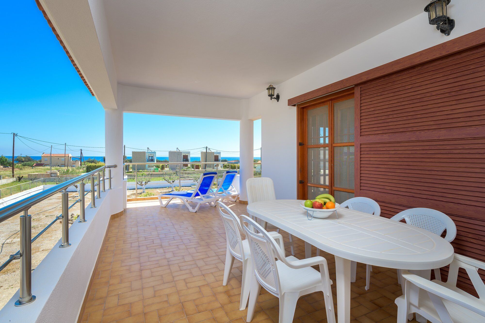 A balcony with a table, chairs, and a fruit bowl.