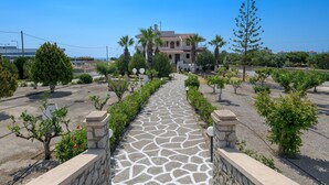 A pathway leading to a building with a tiled roof, surrounded by greenery and stone walls. - Villa Valasia in Gennadi (Gennadi)