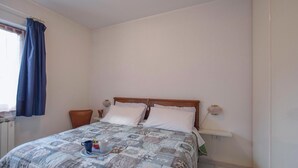 Una camera da letto con un letto, due comodini, una lampada a parete e una finestra con tende.