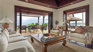 Un vaste espace de vie avec vue sur la mer, un plafond en bois et un coin salon confortable.