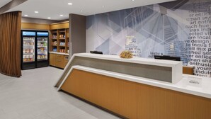 Een receptiezone met een modern ontwerp, met een balie, een muur met tekst en een koelkast gevuld met drankjes.