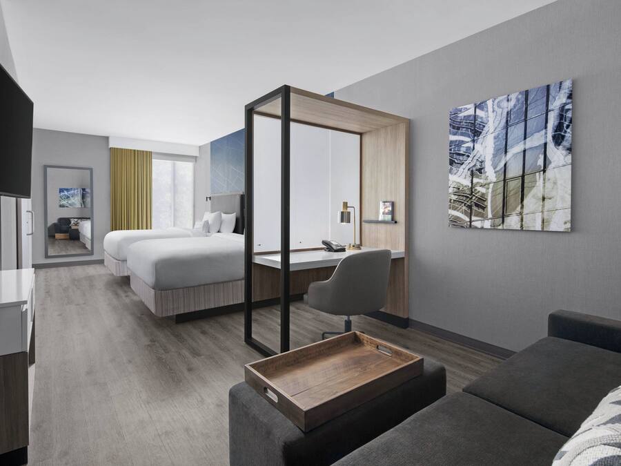 Une chambre d’hôtel moderne équipée d’un grand lit, d’un bureau, d’une chaise et d’un petit coin salon.