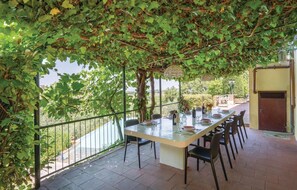 An outdoor dining area with a long table and chairs, surrounded by greenery and a view of the countryside. - Beautiful home in Moncioni with private swimming pool, can be inside or outside (Moncioni)