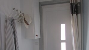 Une salle de bain avec un porte-serviettes, une serviette à rayures, un meuble blanc et une porte avec une fenêtre.