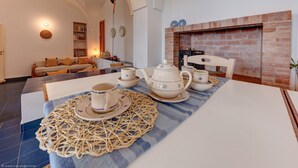 A dining area with a table set for tea, a brick fireplace, and a cozy seating area with a sofa and shelves. - Wonderful seaview w/ direct sea access & jacuzzi (Leuca)