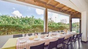 A dining area with a table set for six, large windows, and a view of greenery outside. - Amazing home in Modica with WiFi (Modica)