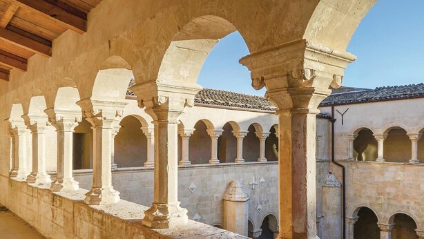 An architectural corridor with arches and columns, leading to a building with a tiled roof. - Amazing home in Modica with WiFi (Modica)