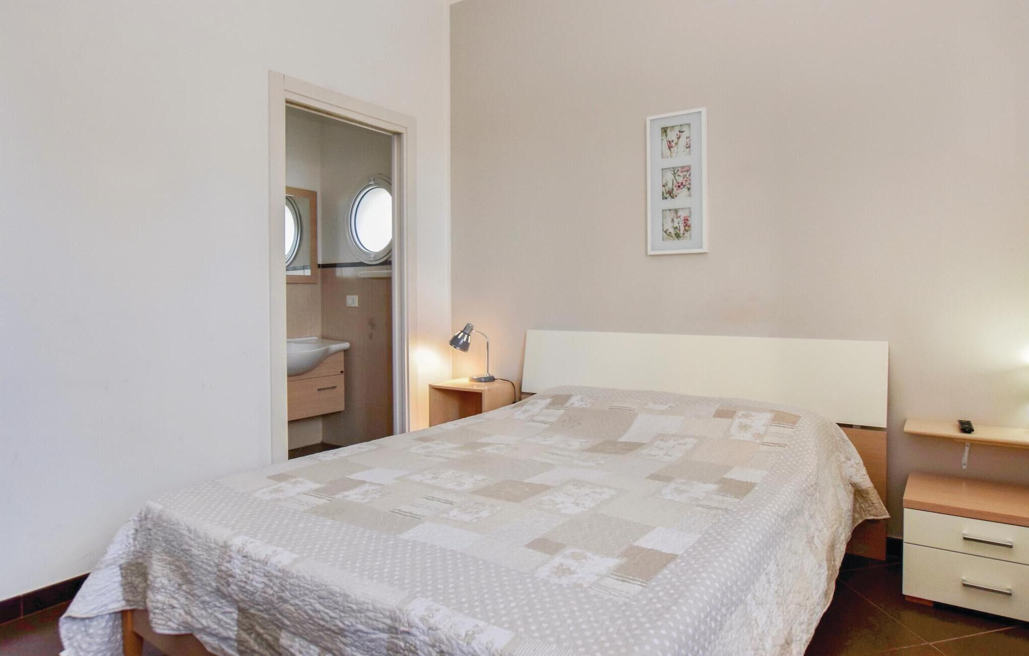 A bedroom with a bed, bedside tables, a nightstand, a mirror, and a framed picture on the wall.