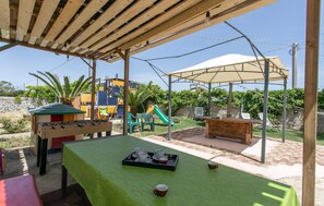 Un'area esterna coperta con un tavolo da calcio, un tavolo con tazze e piattini e un'area giochi con uno scivolo.