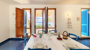 A dining area with a table set for four, wooden shutters on the windows, and a view of the sea. - Direct sea access and stunning location (Leuca)