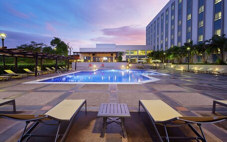A pool area with lounge chairs, a table, and a building in the background.