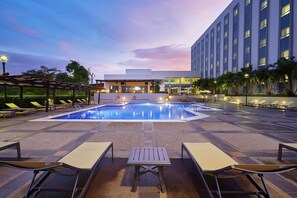 A pool area with lounge chairs, a table, and a building in the background.