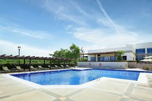 A swimming pool with lounge chairs and a building in the background.