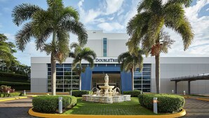 A DoubleTree hotel with a central fountain, palm trees, and a modern building facade. - DoubleTree by Hilton Managua (Managua)