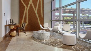 A spacious lobby with a marble reception desk, modern chairs, and large windows offering a view of the parking area. - DoubleTree by Hilton Managua (Managua)