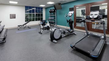Un gimnasio con cintas de correr, elípticas y pesas sueltas.