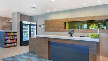A reception area with a counter, a refrigerator stocked with beverages, and a snack display.