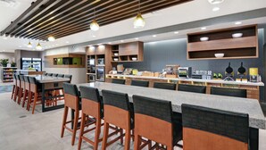 Un restaurant moderne avec un long comptoir, des tabourets de bar et des étagères en bois.