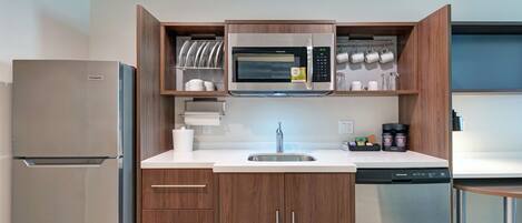 A modern kitchen with a built-in microwave, stainless steel refrigerator, and dishwasher.