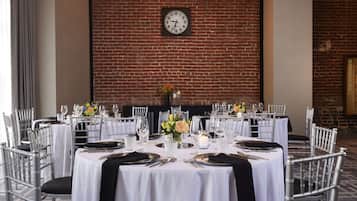 A formal dining setup with round tables, white tablecloths, and silver chairs.