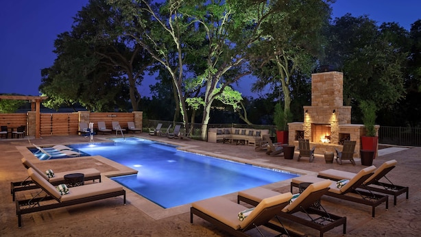 Un espace extérieur avec une piscine, des chaises longues et une cheminée en pierre.