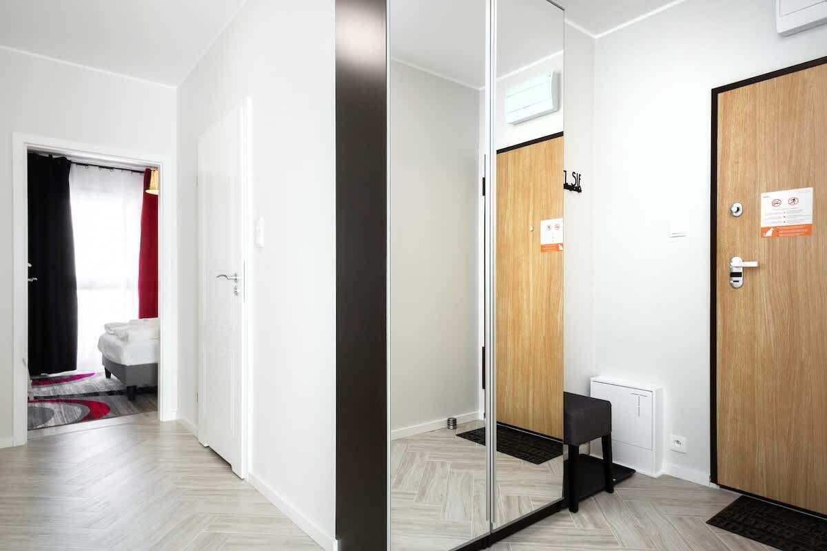 Een hotelkamer met een houten deur, een klein bankje en een radiator.