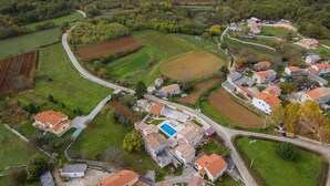 An aerial view of a rural village with houses, fields, and a winding road.