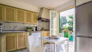 A compact kitchen with a dining area, a dishwasher, and a view of a garden through an open door. - 3 bedroom beautiful home in Imperia -IM- (Imperia -IM-)