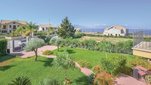 Un quartier résidentiel avec des maisons, un jardin bien entretenu et une vue dégagée sur la mer.