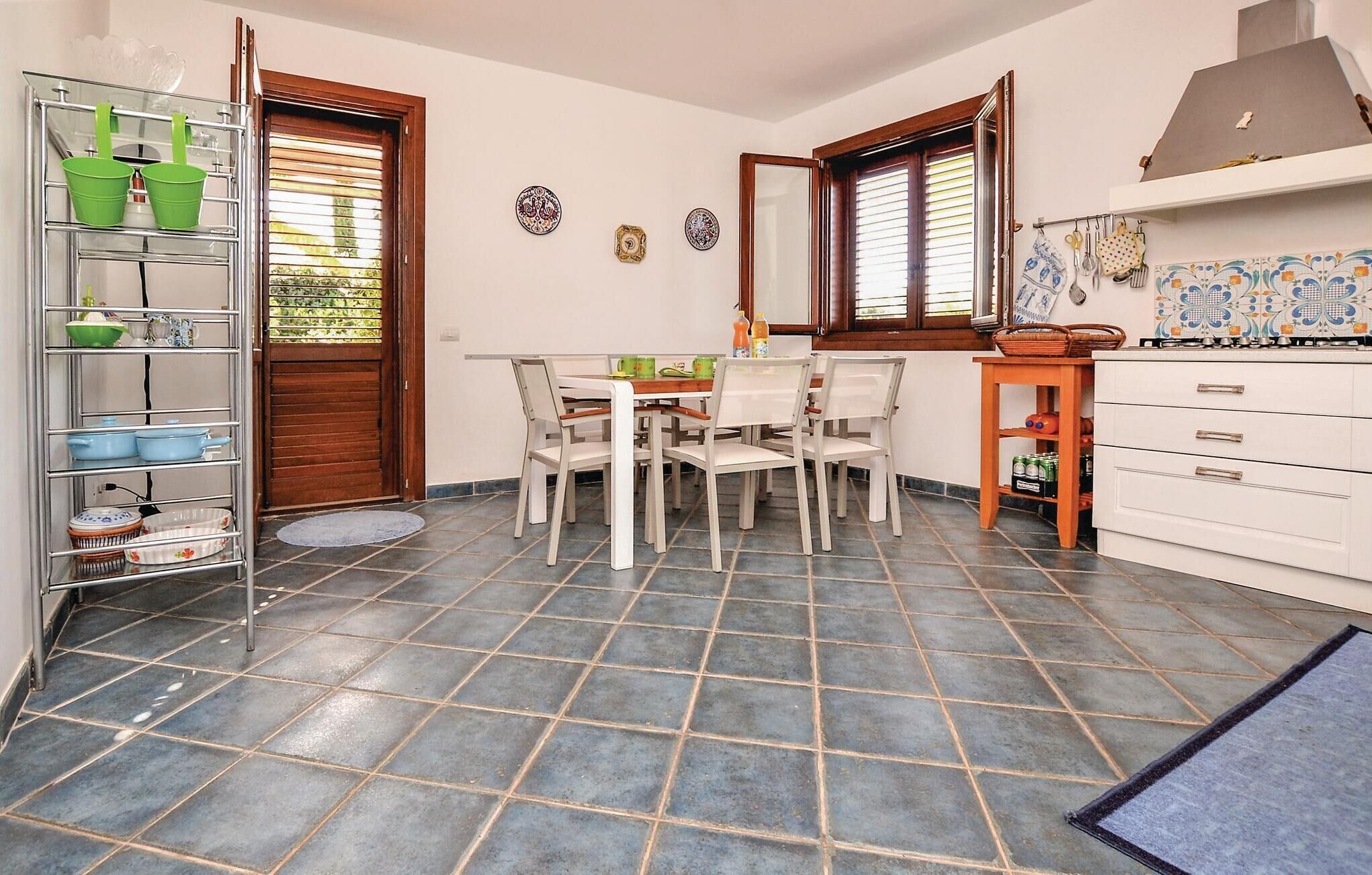 Une cuisine compacte comprenant une table à manger, des chaises, un petit meuble et un sol carrelé.