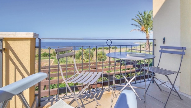 Un balcon avec vue sur la mer, une table et deux chaises.