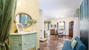 A living room with a blue sofa, a green cabinet with decorative carvings, a round mirror, and a dining area with a table and chairs. - Amazing home in Montebuono (Montebuono)