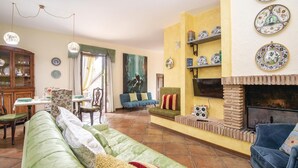 A cozy living room with a green sofa, a blue armchair, a fireplace, and a dining area with a wooden cabinet and table. - Amazing home in Montebuono (Montebuono)