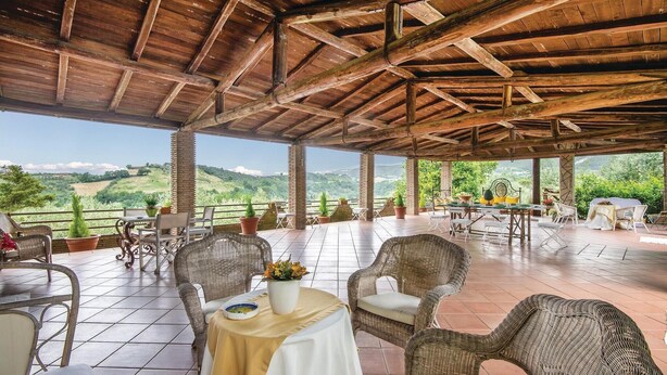 An outdoor patio with wicker furniture and a table set for dining, overlooking a scenic landscape. - Amazing home in Montebuono (Montebuono)