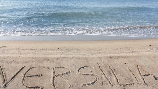 En strand där ordet ”VERSILIA” är skrivet i sanden.