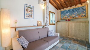Una sala de estar acogedora con un sofá marrón, un mueble de madera y un cuadro colorido encima.