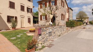 Ein zweistöckiges Steinhaus mit einer Steinmauer und einem gepflasterten Zugang.