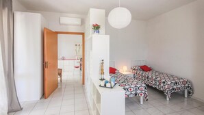 A modern, well-lit room with a bed, bedside table, and a small desk area.