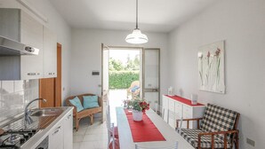 A compact kitchen with a central island, a dining area with a red table runner, and a view of the outdoors.